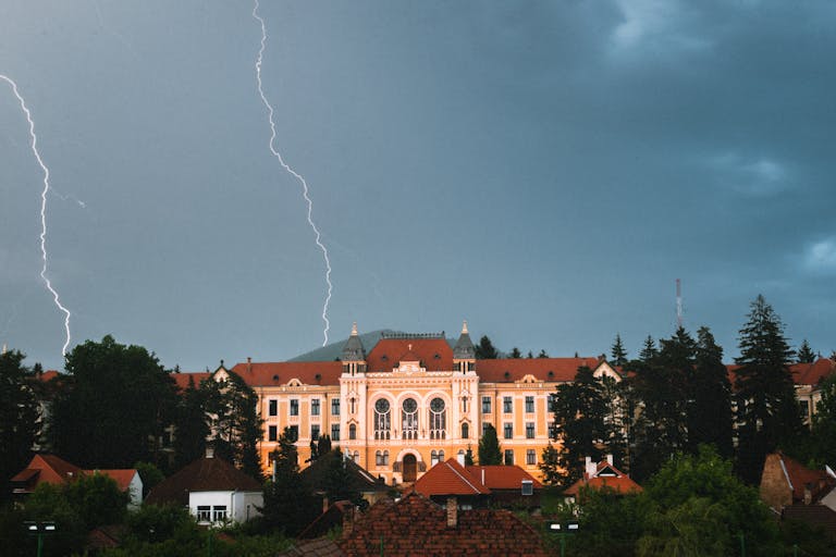 Dramatic view of Márton Áron High School with lightning in Miercurea Ciuc, Romania, highlighting its architecture.